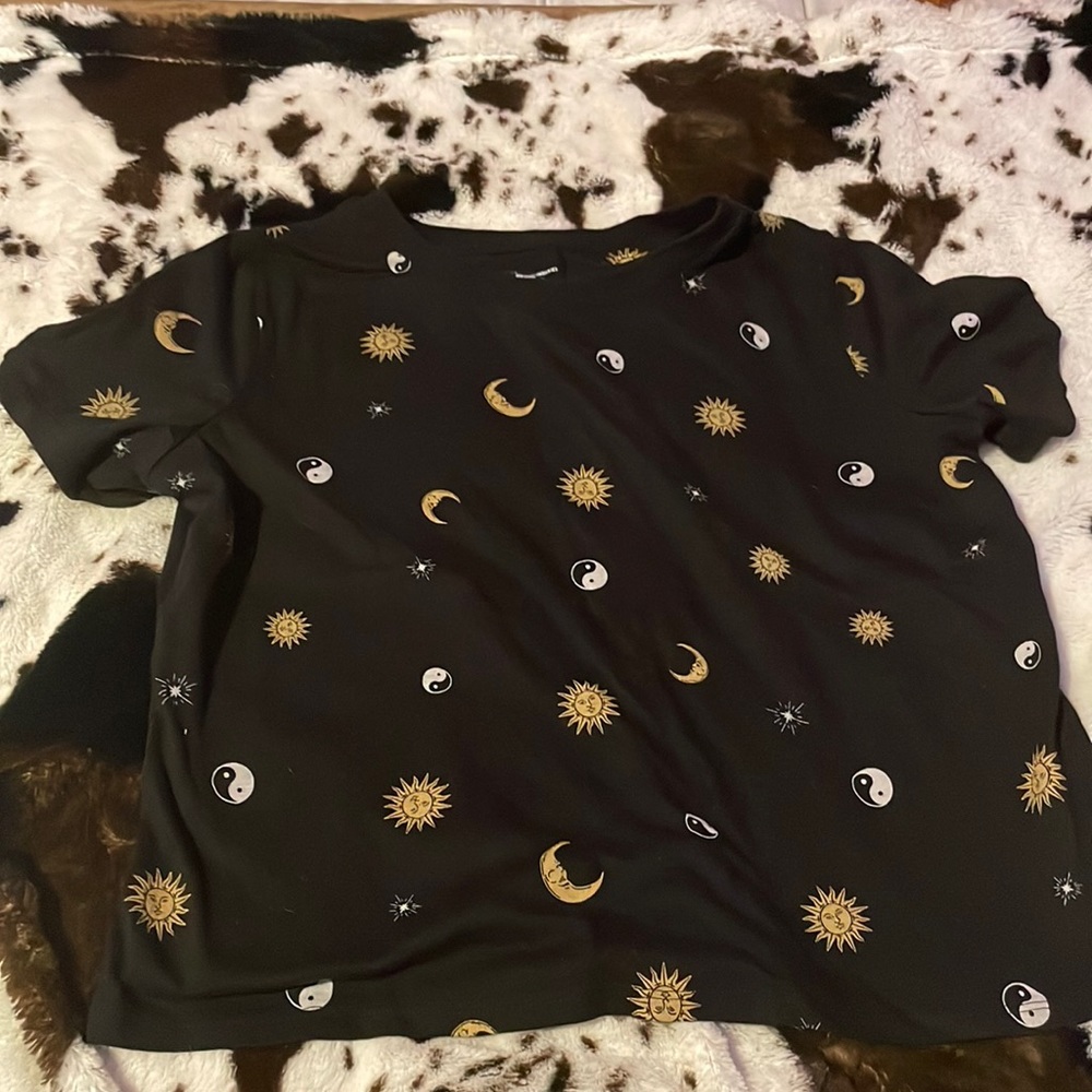 a black tee with moons, suns, and peace signs all over front and back